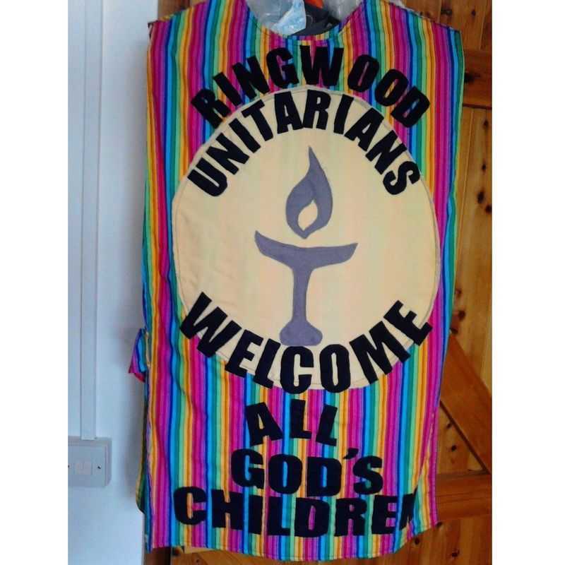 rainbow cloth banner carrying the flaming chalice symbol and the logo 'Ringwood Unitarians welcome all God's children'