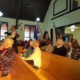 The bagpiper leads the clans in at the beginning of the service