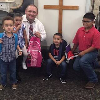 Spanish Pastor Mike Glover and the children with their back to school supplies