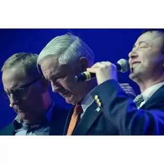 Reverend Jim Solomon, right, of the New Hope Community Church in Newtown, leads the community in an opening prayer. Max Lucado (left) and Bridgeport Mayor Bill Finch (center) listen. By Nick Caito